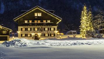 A snow-covered building with illuminated windows and a Christmas tree, surrounded by snow.