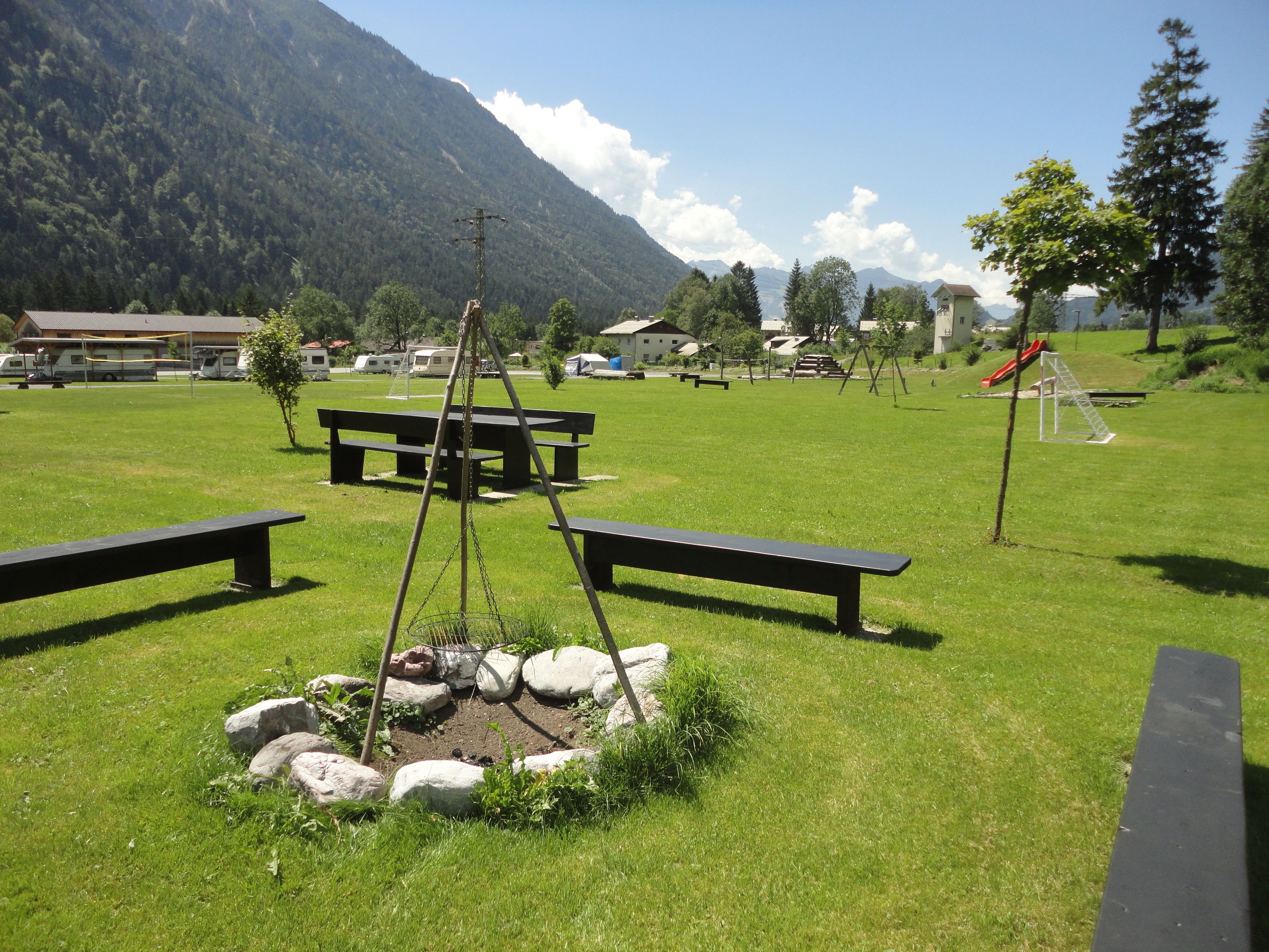 Un'area picnic con panchine e un braciere, circondata da rocce.