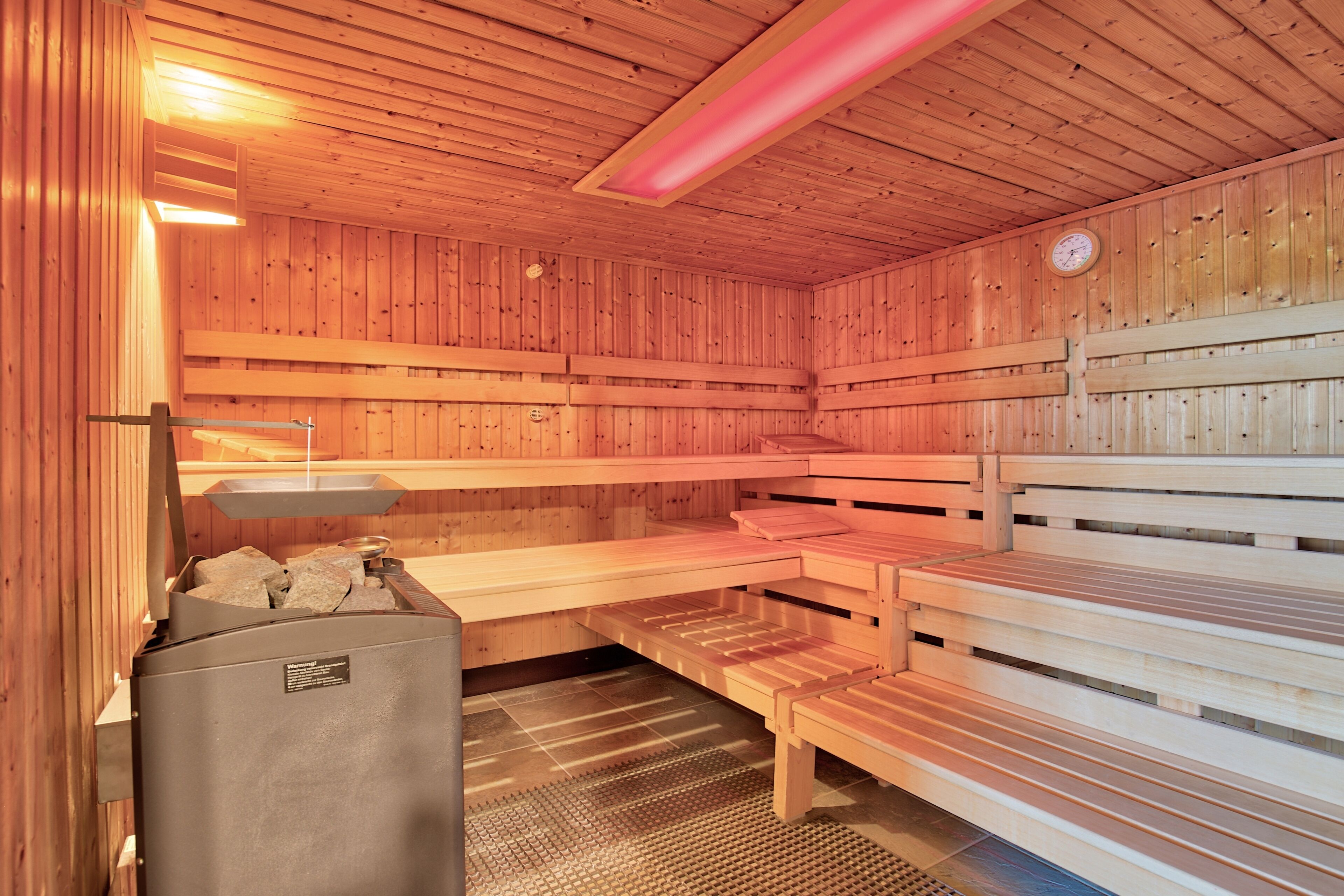 Un sauna avec des bancs en bois et un lavabo.