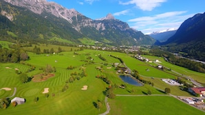 A golf course with a lake, surrounded by mountains and a small village. - Landhaus Walch (Innerbraz)
