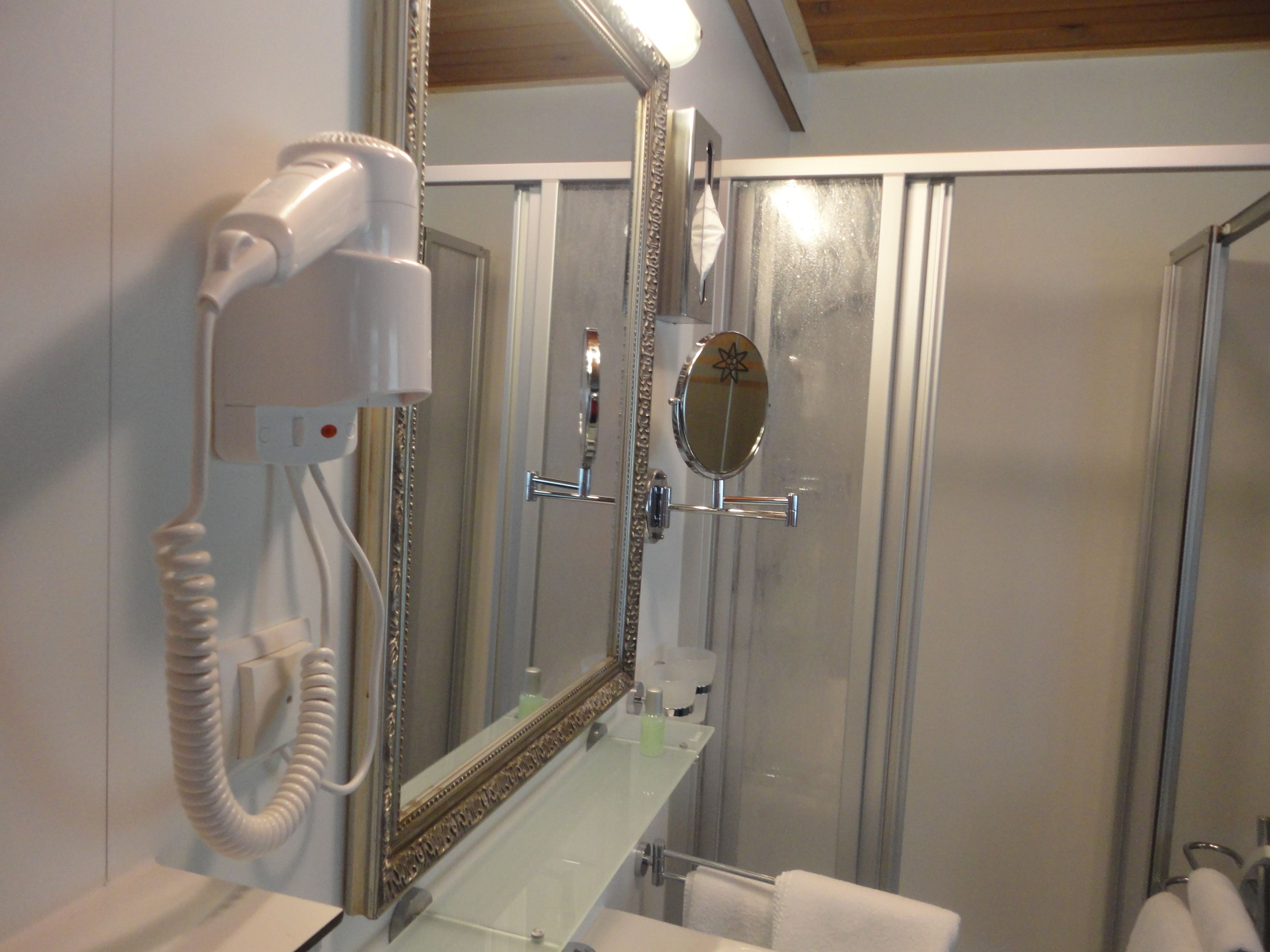 Un baño con secador de pelo, espejo y ducha.
