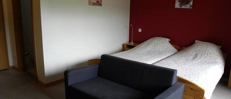 A bedroom with a bed, a sofa, and two wall-mounted lamps.