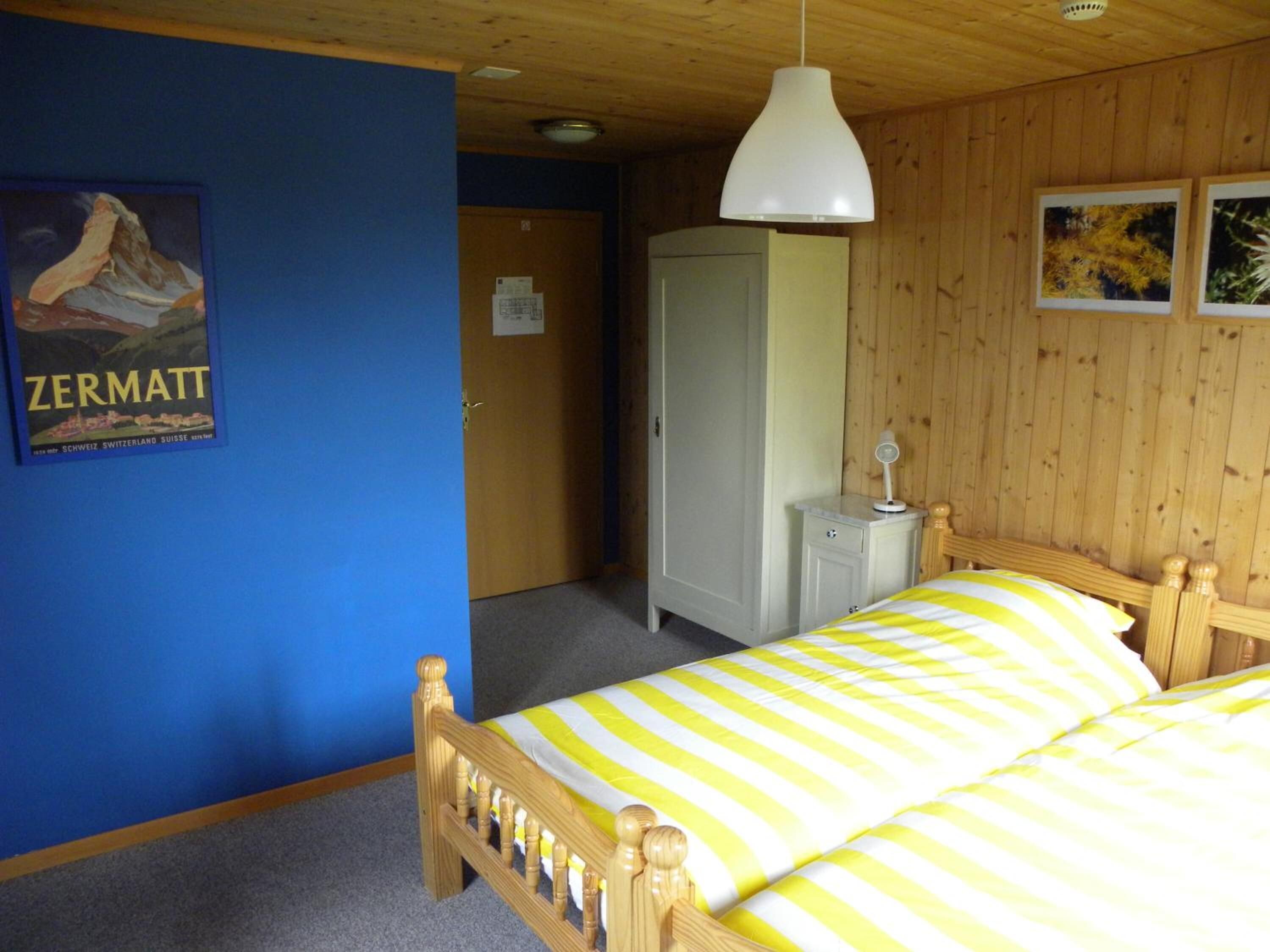 A bedroom with a bed, a wardrobe, a mirror, and a poster on the wall.