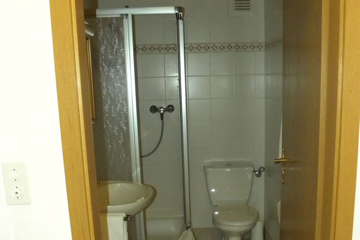 A small bathroom with a shower, toilet, and sink.