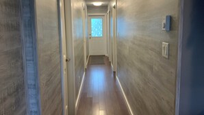 A narrow hallway with wooden flooring and light-colored walls. - Riverside Motel (Port Alberni)