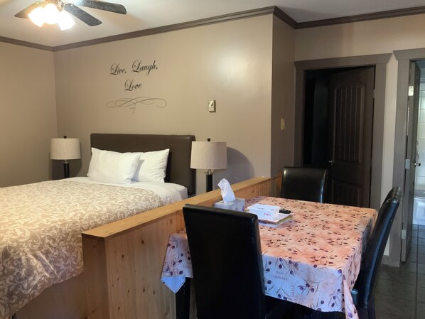 A hotel room with two single beds, a wooden desk with a table, a chair, and a door.