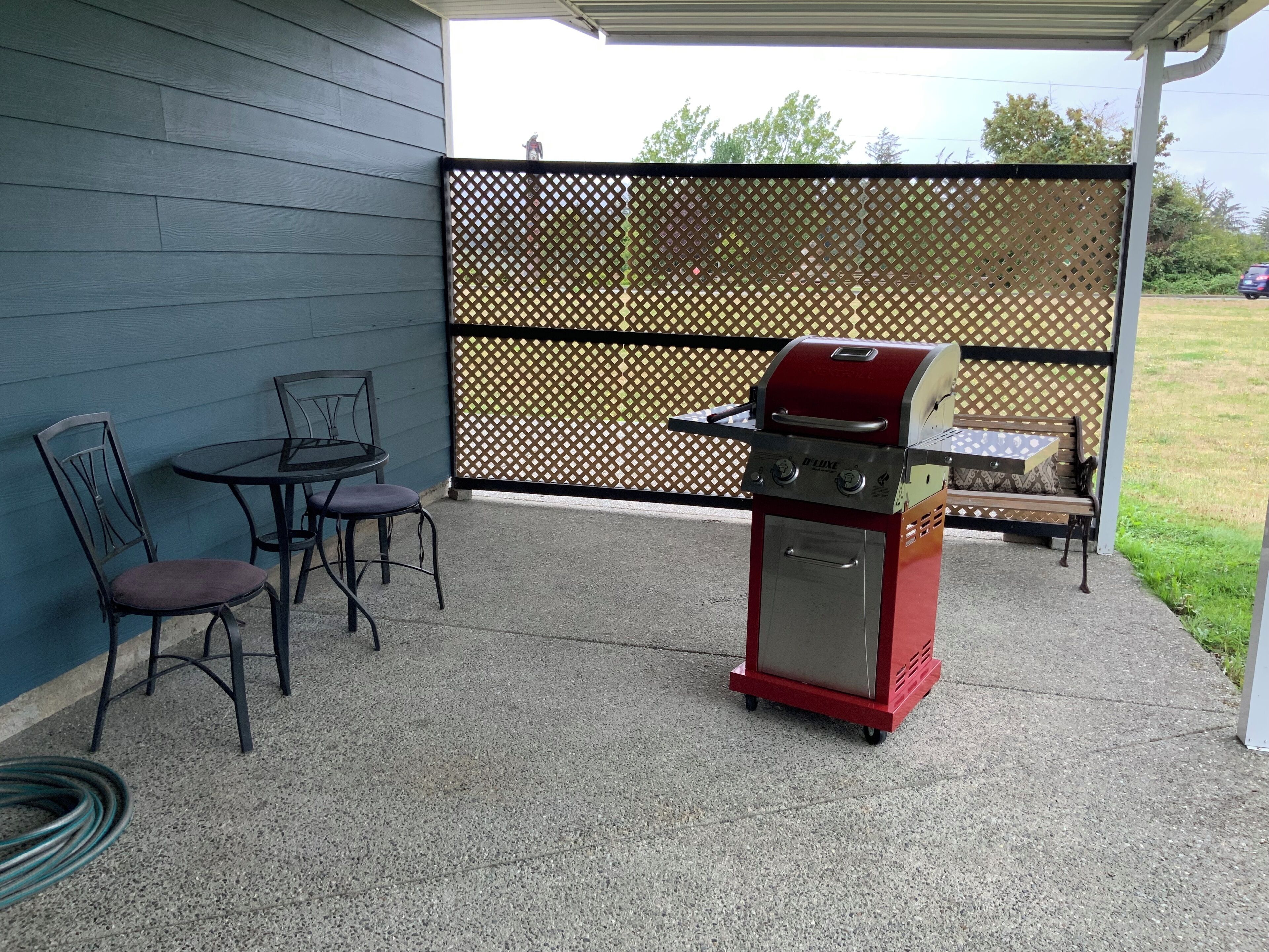 Una parrilla, una mesa con sillas y un patio cubierto con cerramiento.