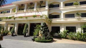 A multi-story building with a traditional architectural style, featuring a central entrance with steps, balconies, and potted plants. - Lin Ratanak Angkor Hotel (Siem Reap)