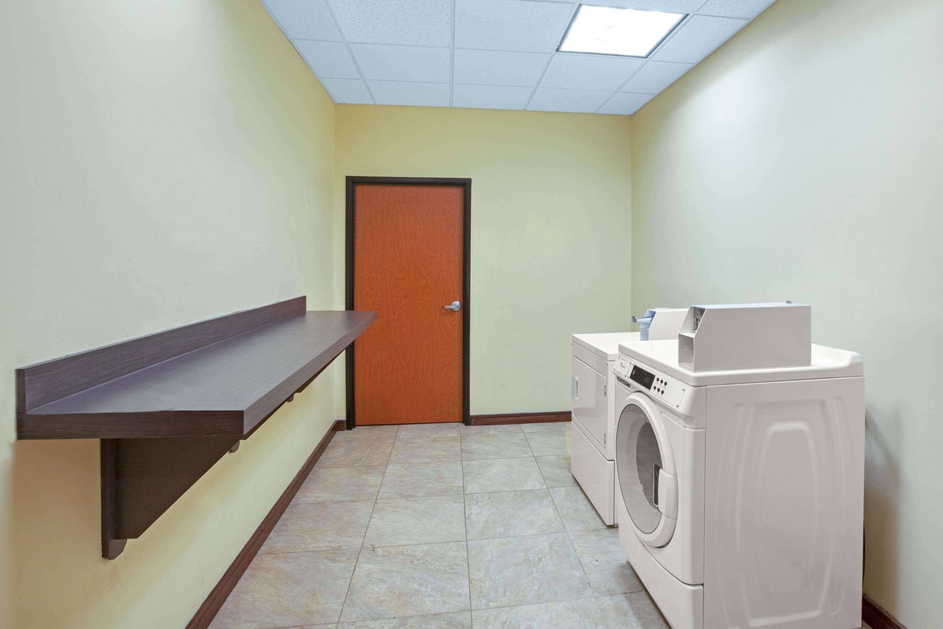 Une buanderie équipée d’un lave-linge, d’une étagère et d’une porte.