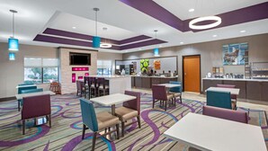 A hotel lobby with a bar area, seating arrangements, and a view of the outdoors.