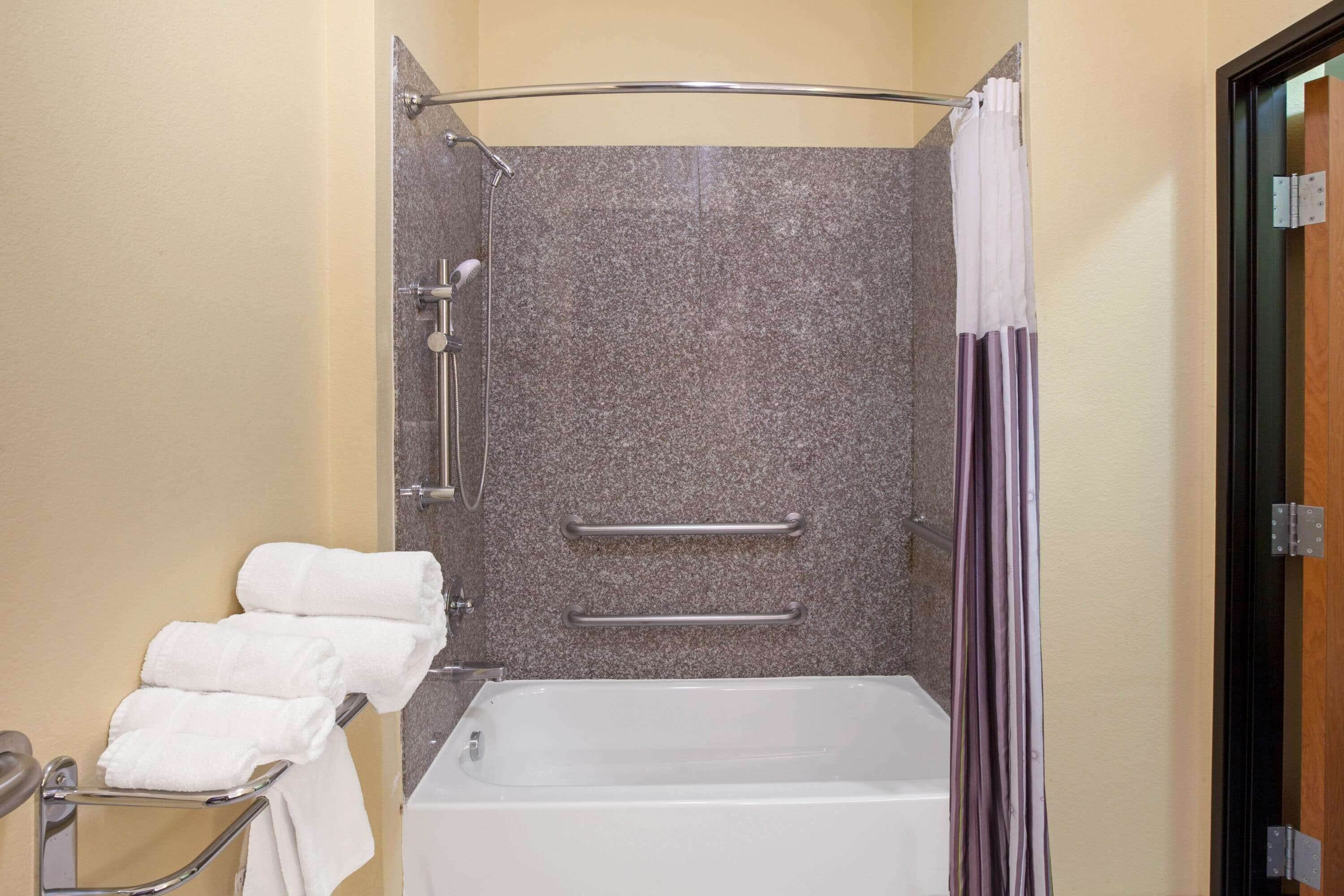 A bathroom with a shower, a bathtub, and a towel rack.