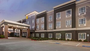 A hotel with a modern facade, a covered entrance, and a parking area with handicapped spaces.