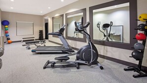 A gym with treadmills, an elliptical, and a weight rack with various exercise balls.
