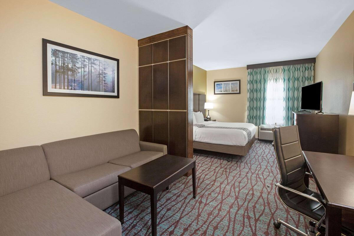 Una habitación de hotel con sofá, cama, escritorio y televisor.