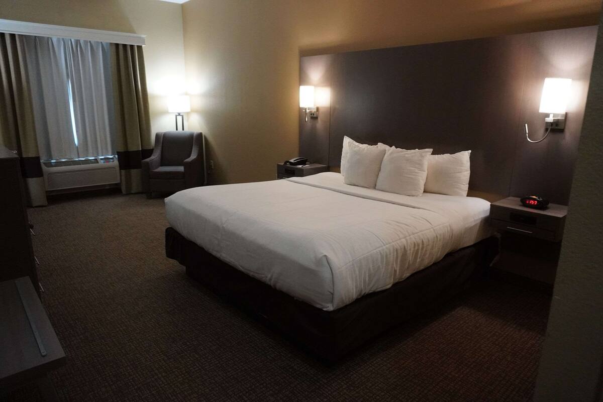 A hotel room with a large bed, two bedside tables, a chair, a desk, and a lamp.
