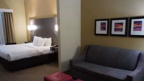 A hotel room with a bed, a sofa, and three framed pictures on the wall. - Comfort Inn & Suites Monahans I-20 (Monahans)