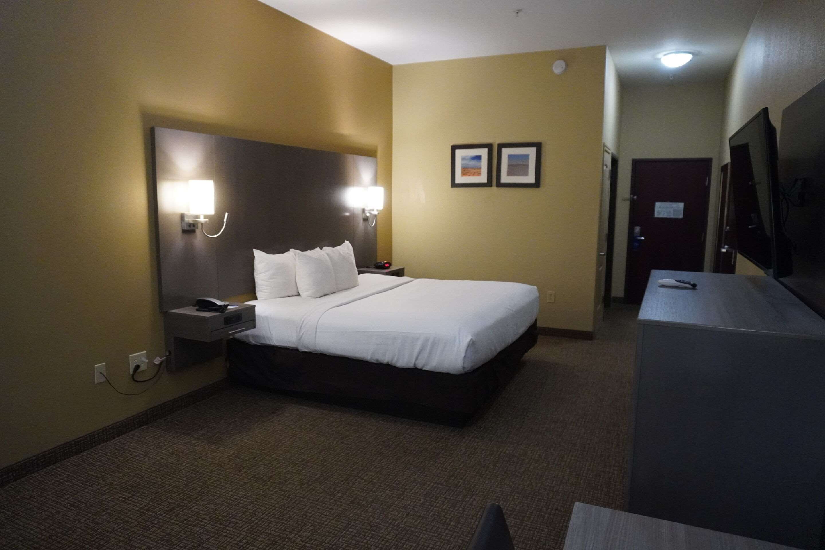 A hotel room with a large bed, bedside lamps, a desk, and a television.