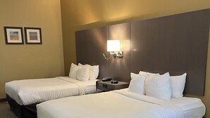 A hotel room with two beds, a nightstand, a wall-mounted lamp, and two framed pictures on the wall. - Comfort Inn & Suites Monahans I-20 (Monahans)