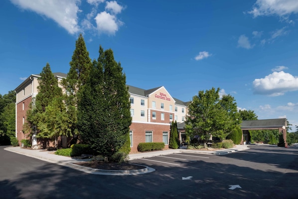 A hotel with a brick facade, a covered entrance, and a parking lot.