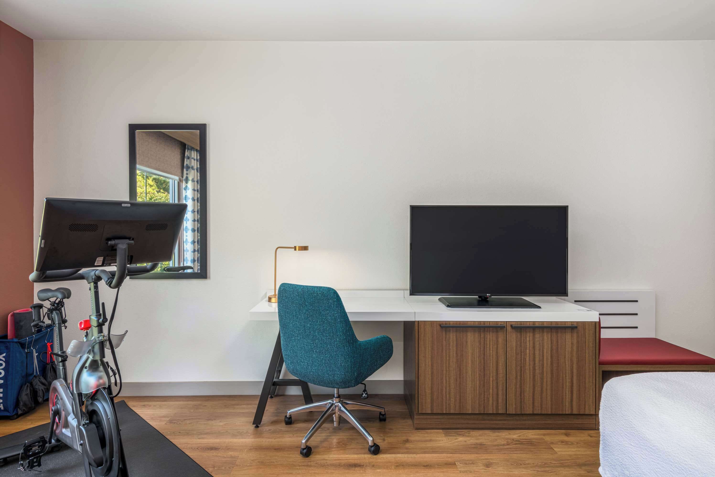 A modern room with a desk, a chair, a bed, and a bicycle.