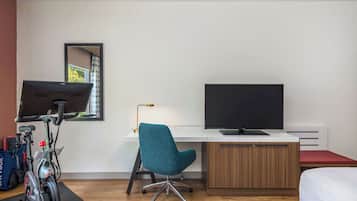 A modern room with a desk, a chair, a bed, and a bicycle.