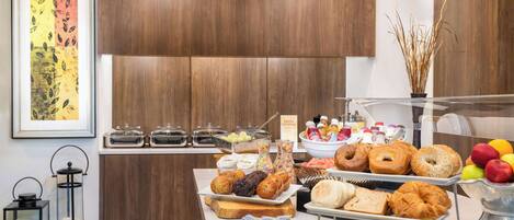 A breakfast buffet with various pastries, fruits, and beverages.