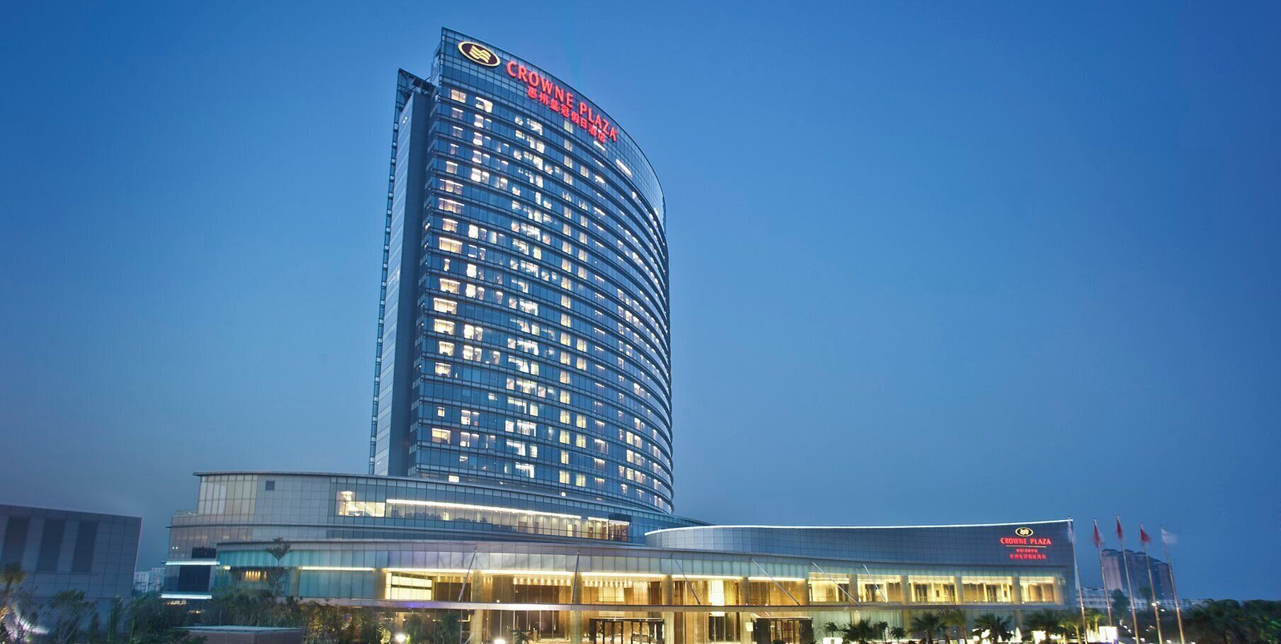 A high-rise hotel with a curved facade, multiple floors, and illuminated windows.
