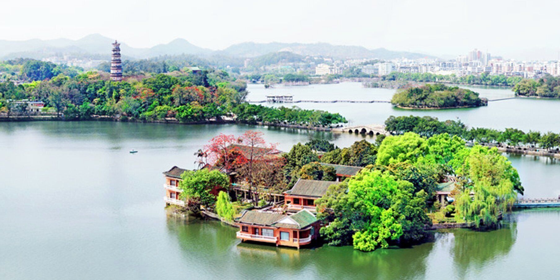 A traditional building with a thatched roof, surrounded by lush greenery and a calm lake.