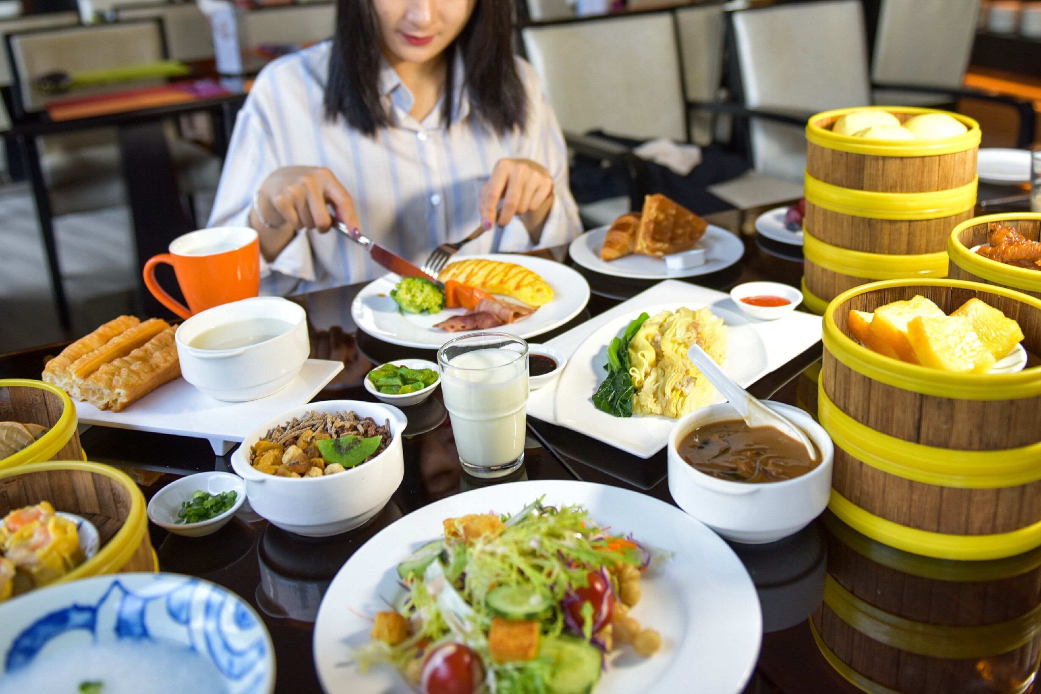 A dining table with various dishes, including a salad, bread, and a bowl of soup.
