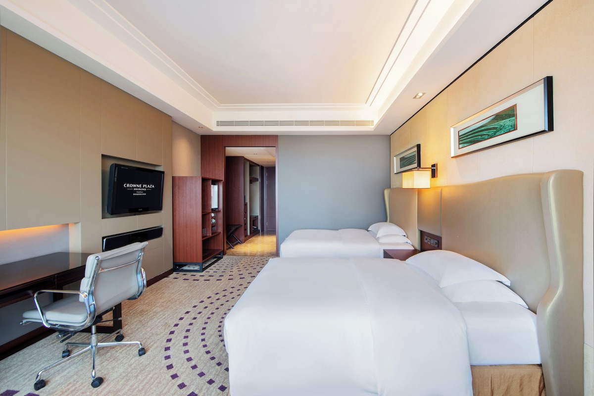 Una habitación de hotel con una cama grande, un escritorio con una silla, un televisor y un cuadro en la pared.