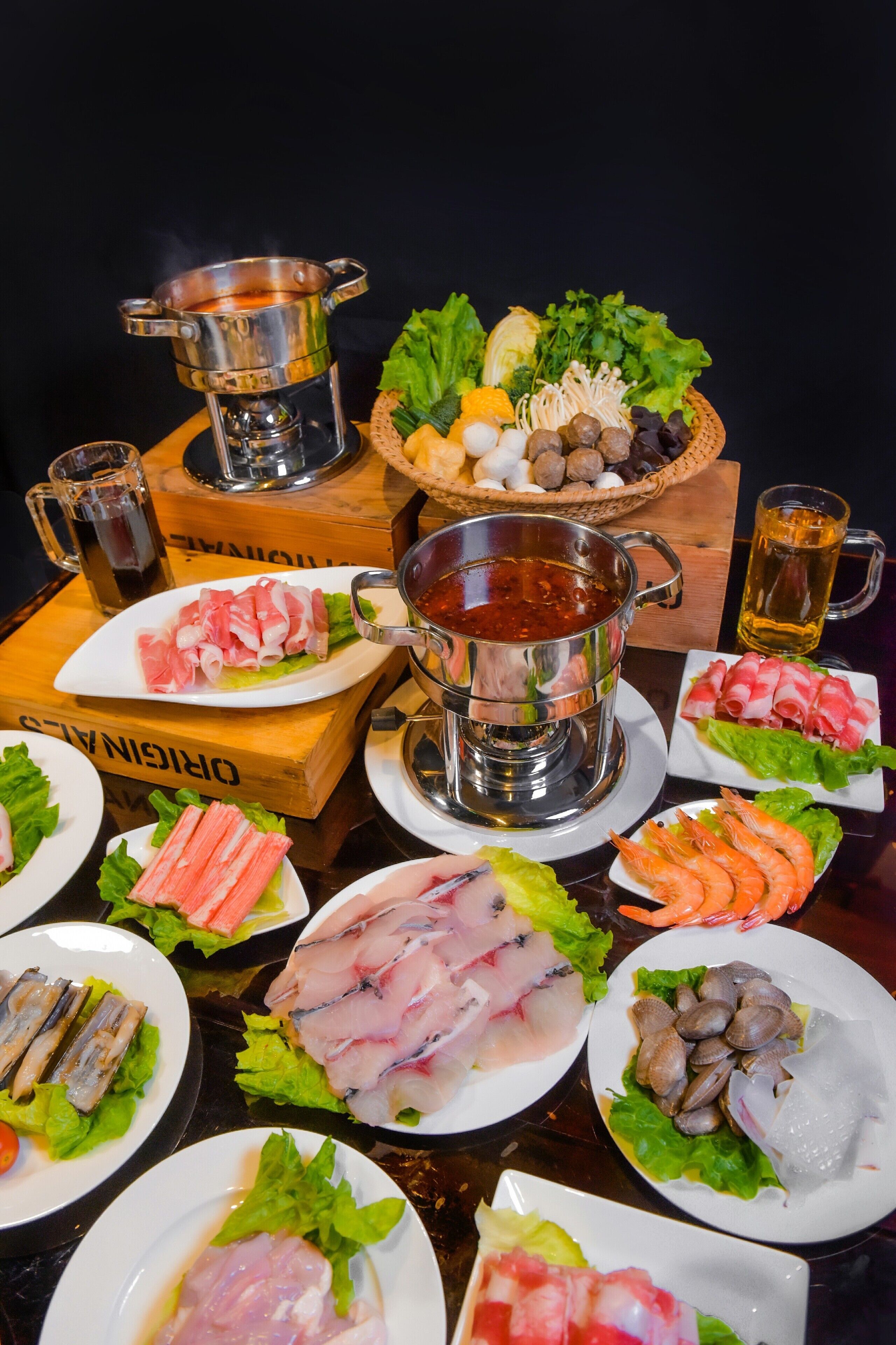 A variety of seafood dishes and a hot pot setup on a table.