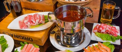 A variety of seafood dishes and a hot pot setup on a table.