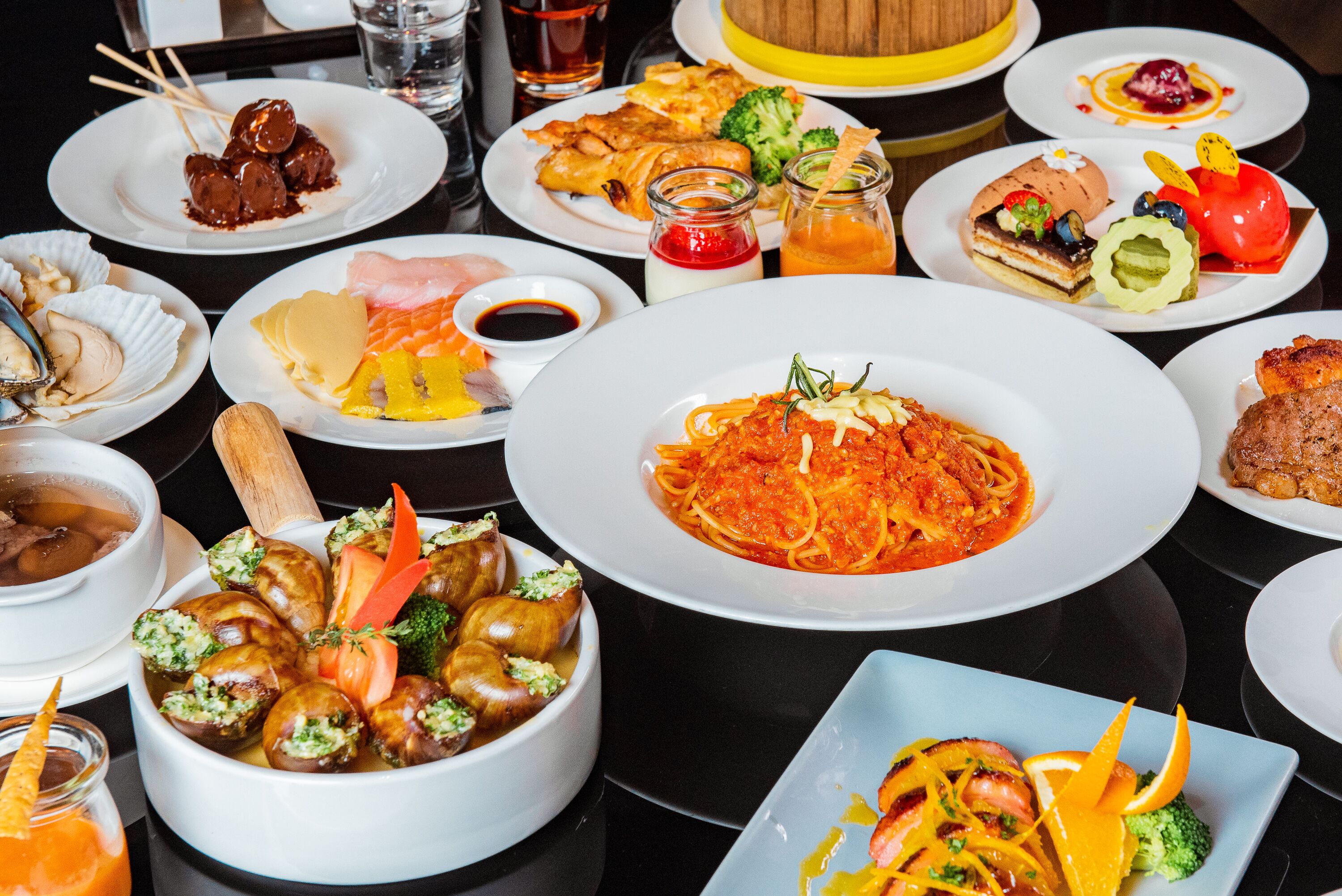 Une variété de plats sont disposés sur la table, notamment des pâtes, des fruits de mer et des légumes.