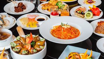 Une variété de plats sont disposés sur la table, notamment des pâtes, des fruits de mer et des légumes.