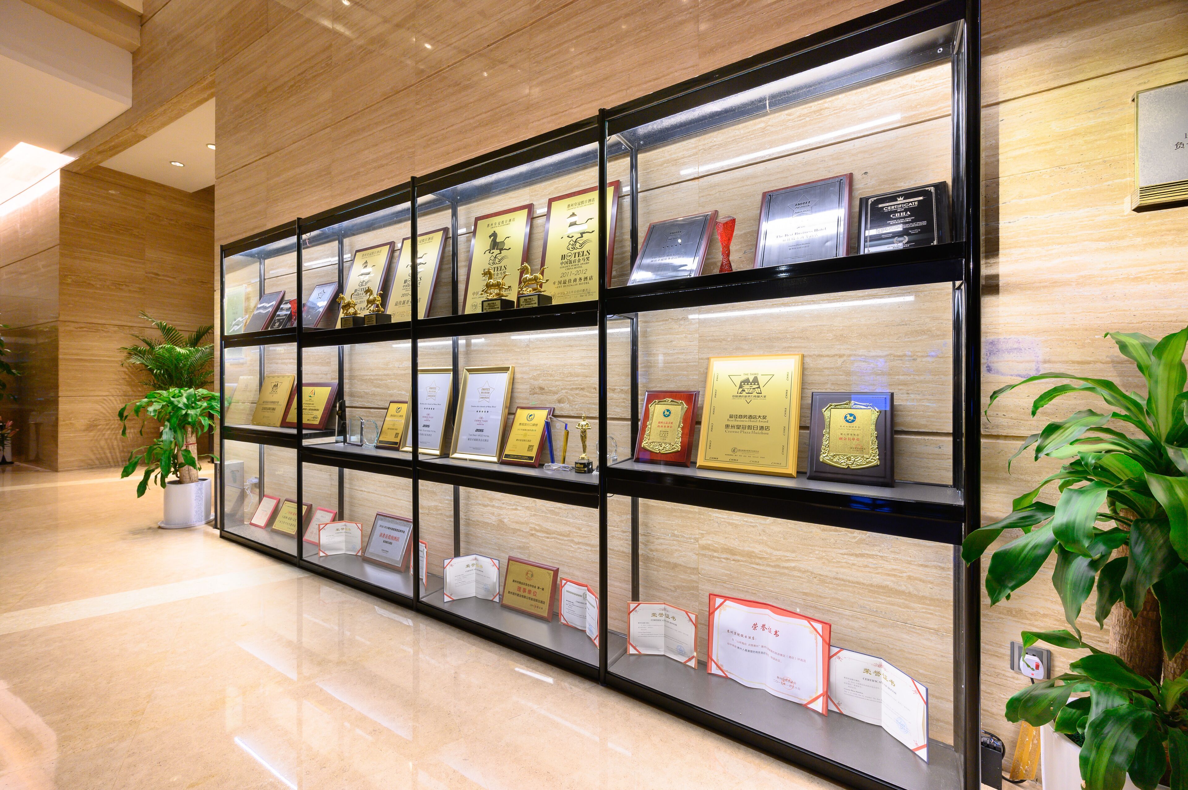 A display of framed awards and certificates in a lobby with a polished floor and wooden walls.