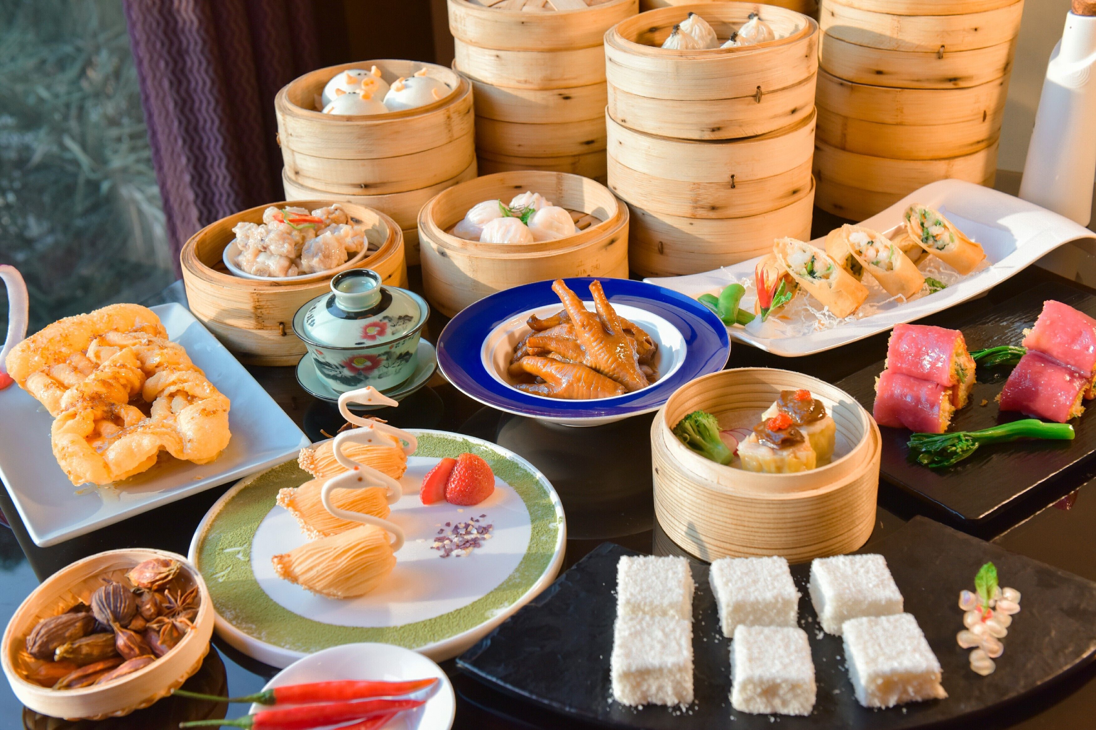 A variety of Asian dishes including dumplings, sushi, and other appetizers arranged on a table.