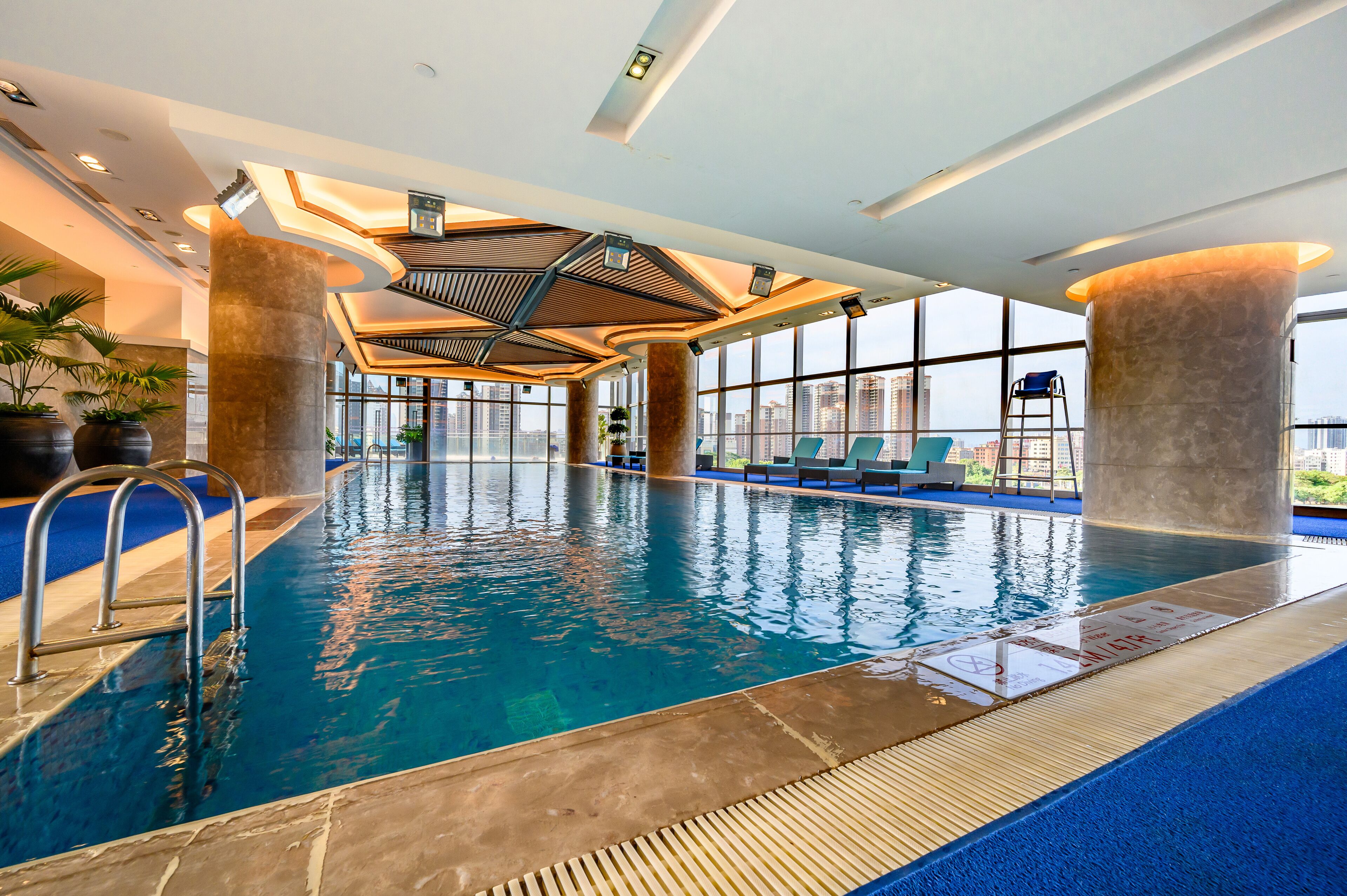 An indoor swimming pool with clear blue water, surrounded by large windows and modern architectural design.