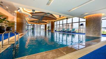 An indoor swimming pool with clear blue water, surrounded by large windows and modern architectural design.