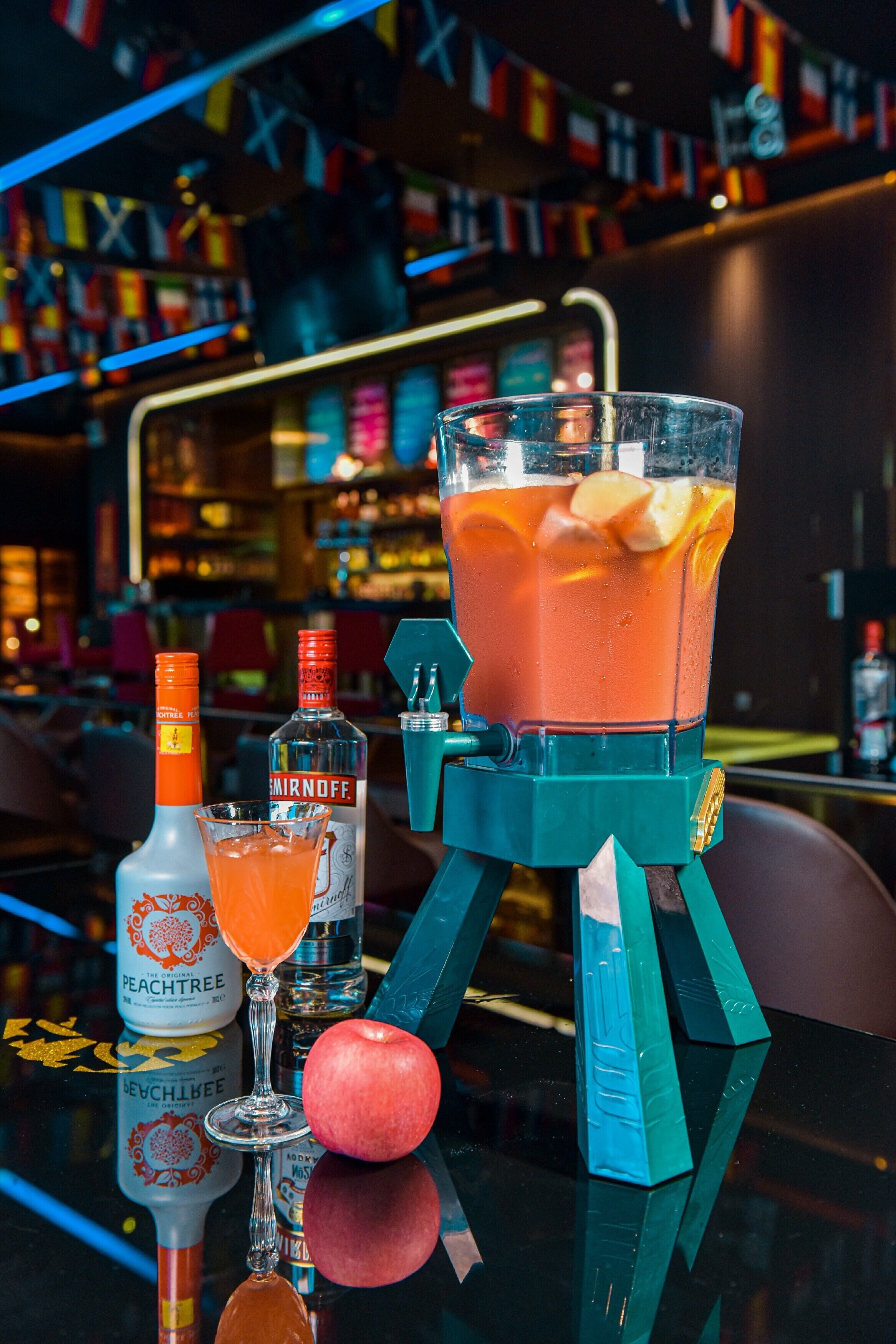 Un bar avec un cocktail, deux bouteilles de spiritueux et un verre.