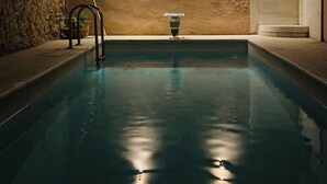 An indoor swimming pool with a stone wall and two wall-mounted lights. - Art Suites Athens (Athens)