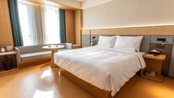 A modern hotel room with a large bed, a seating area with a table, and a view of the outdoors.