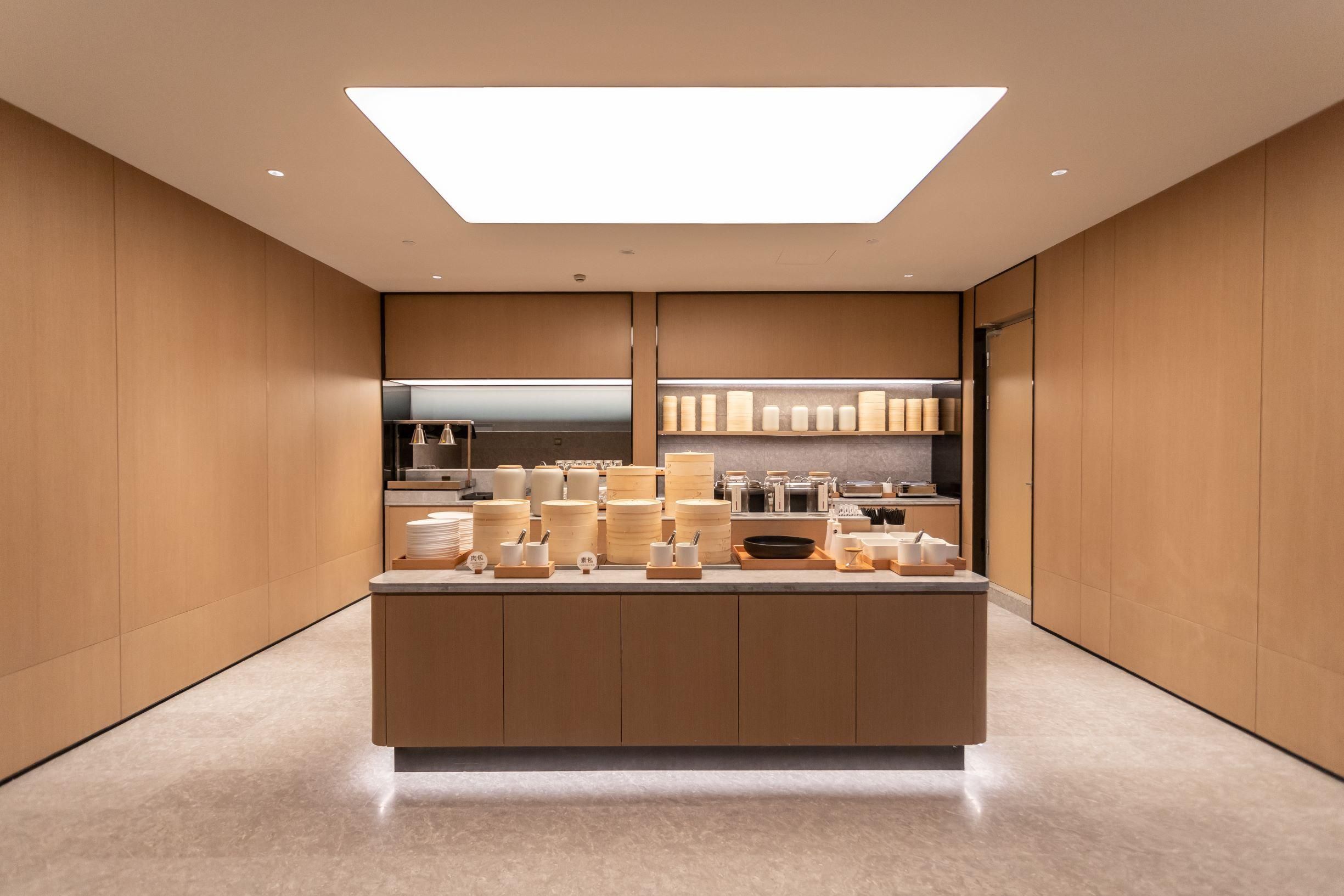A modern kitchen with a central island, wooden cabinetry, and a bright overhead light.
