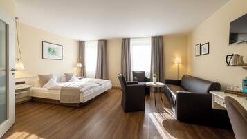 Habitación de hotel con cama, sofá, una mesita y televisión.