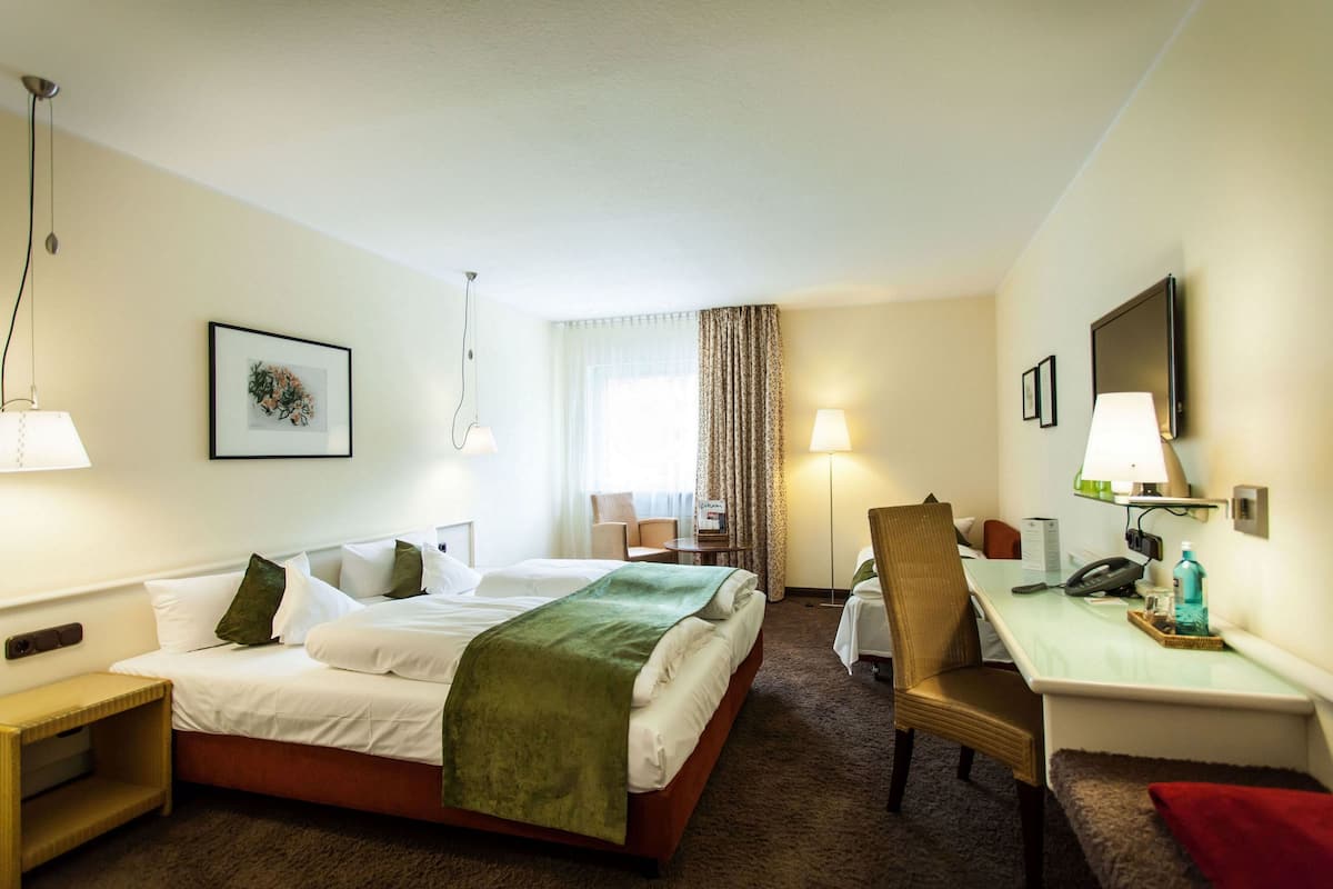 A hotel room with a bed, desk, chair, and lamps.