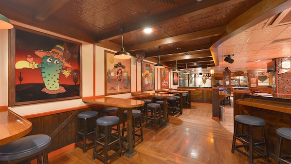 L’intérieur d’un restaurant avec des tables en bois, des tabourets de bar et des peintures murales.