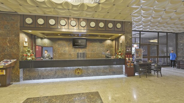 A hotel reception desk with clocks displaying times for New York, Cairo, London, Bombay, Hong Kong, Tokyo, and Moscow. -  Grand Astoria Hotel (Dubai)