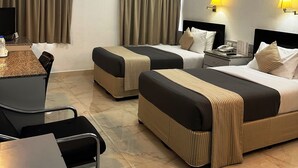 A hotel room with two beds, a desk, a chair, a table, a telephone, and two wall-mounted lamps. -  Grand Astoria Hotel (Dubai)