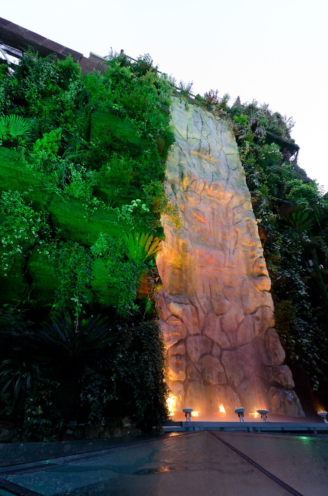 A rock wall with a waterfall feature and seating area.