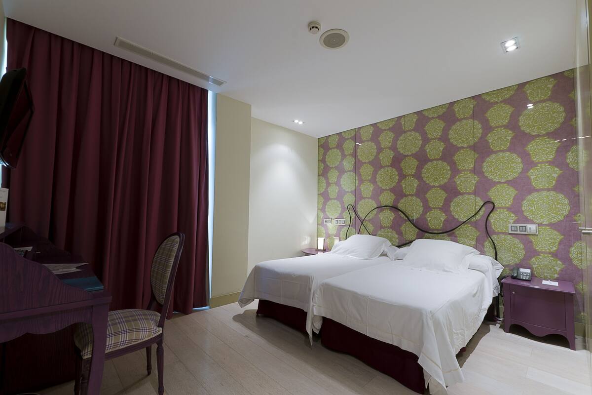 A hotel room with two beds, a desk, and a chair.