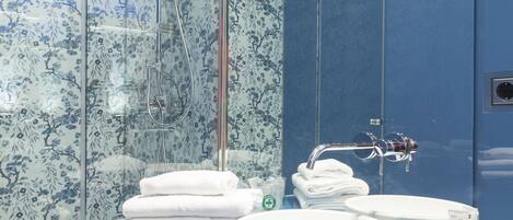 A modern bathroom with a glass shower enclosure, a blue vanity, and a large mirror.
